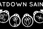 Black logo with 'BEATDOWN SAINTS' text above four white circular emblem pendants featuring floral drawings, flanked by stylized wings on a black background.